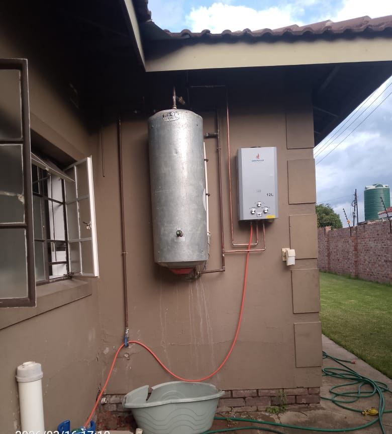 Twelve-litre gas water heater plumbed in copper alongside an existing geyser on an outside wall