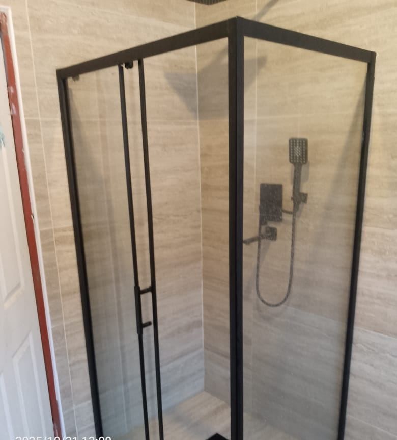 Black-framed sliding shower enclosure with matt black shower set and a linear drain