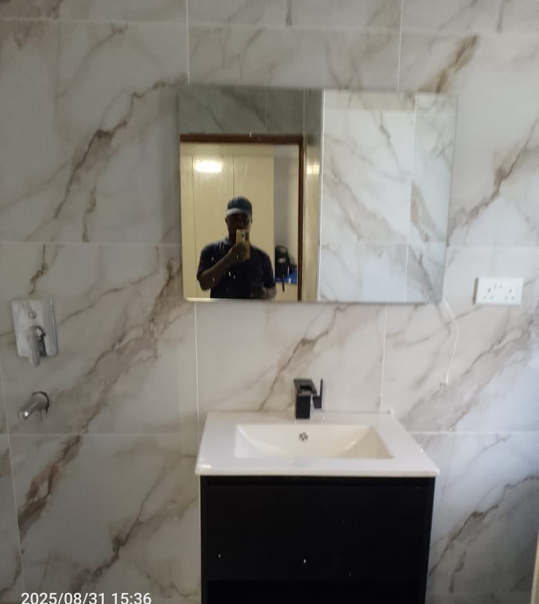 Black wall-hung vanity unit with basin, matt black mixer and mirror against marble tiling