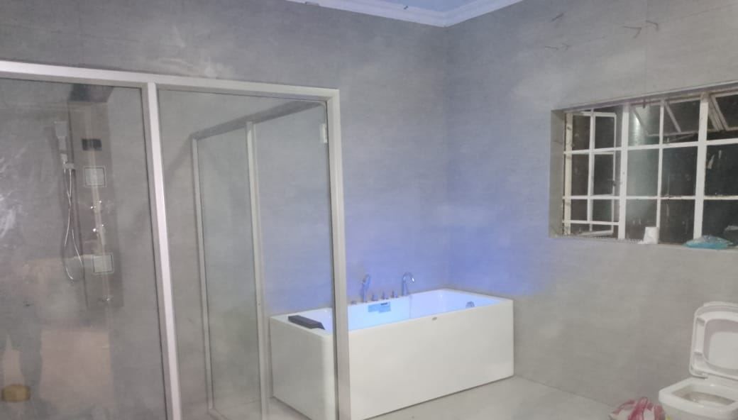 Whirlpool bath filled and lit during commissioning, next to a framed shower enclosure